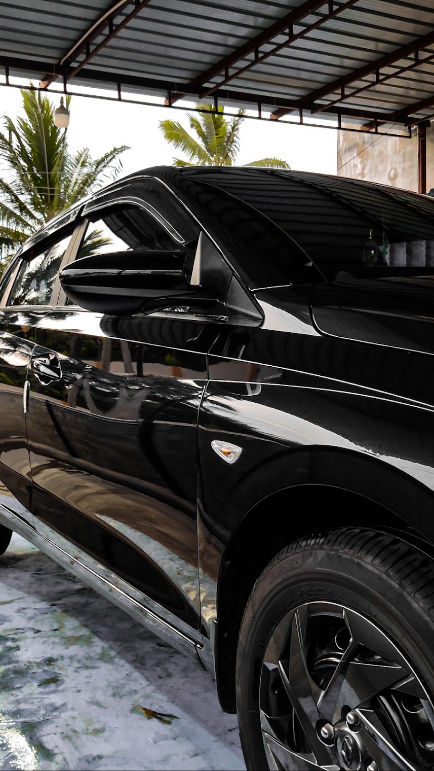 Max technician in branded gloves using a flashlight to inspect a silver sedan rocker panel for damage before and after washing